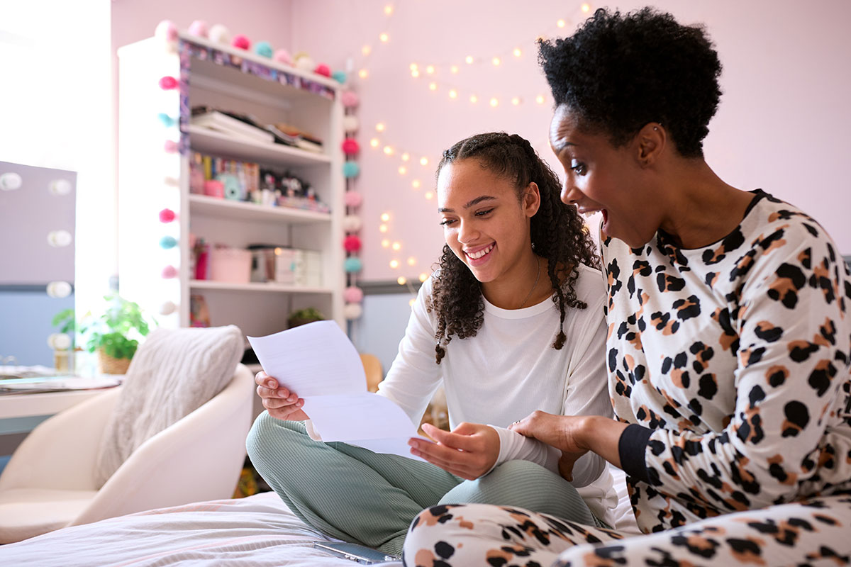 girl reading paper with her mom, smiling