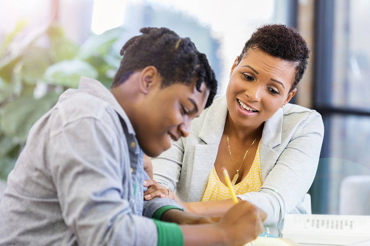Undergraduate male student working on homework while mother helps